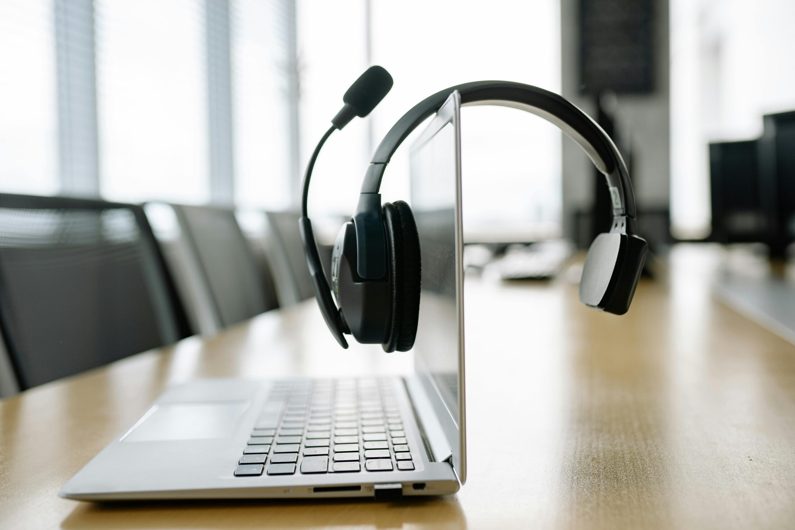 voip call monitoring headset and laptop on wooden desk